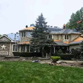 Photo of house surrounded by pine trees during construction re-roof project.